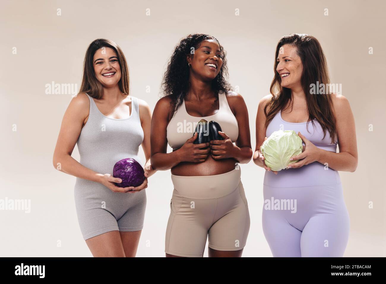 Femmes enceintes multiculturelles tenant des fruits et légumes représentant la croissance hebdomadaire du bébé, Groupe des mères attendues dans le troisième trimestre St Banque D'Images