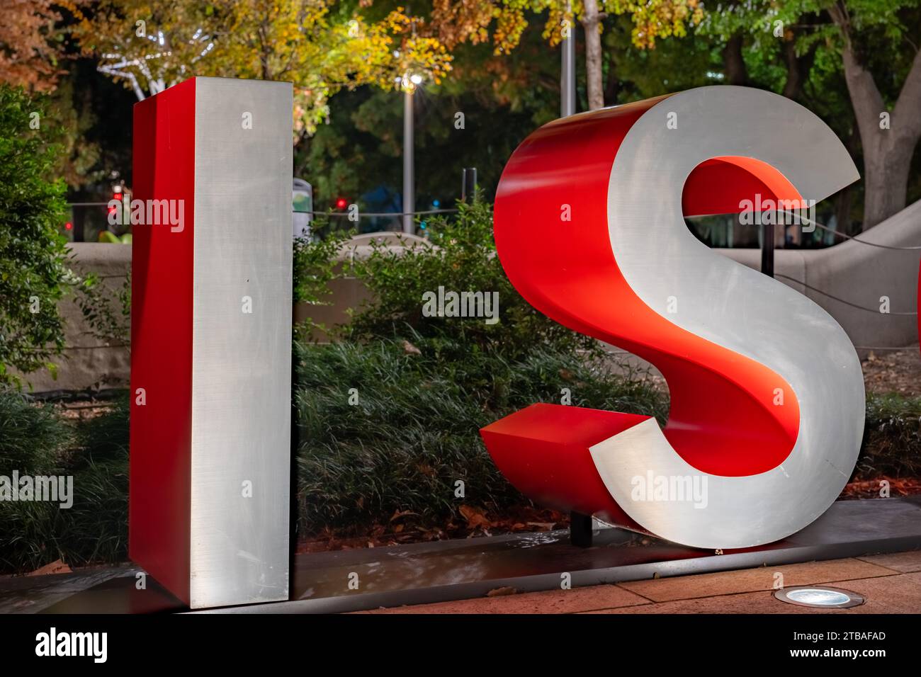 Lettres 3D tridimensionnelles rouges et grises formant le mot EST avec un fond extérieur de soirée. Banque D'Images