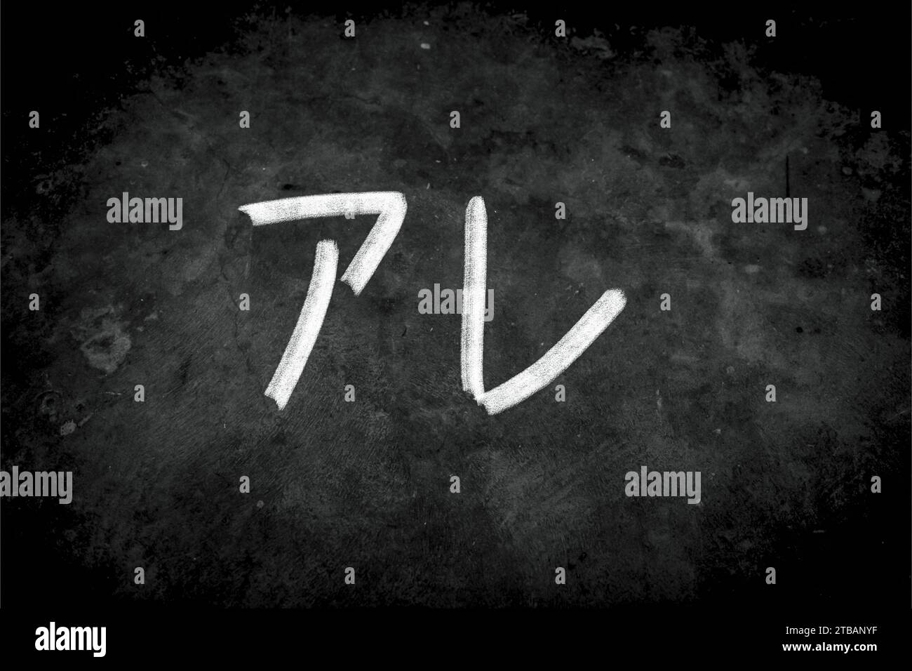 Gros plan de la phrase “アレ” (are, a.r.e.) par écriture à la craie blanche sur tableau noir. La surface du tableau noir est poudreuse et rugueuse Banque D'Images