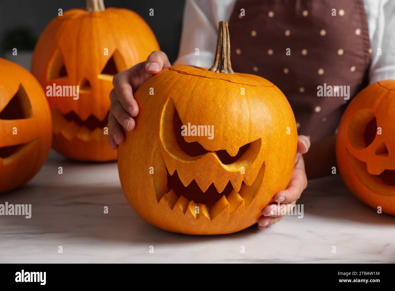 Femme avec des citrouilles sculptées pour Halloween à la table en marbre blanc, closeup Banque D'Images