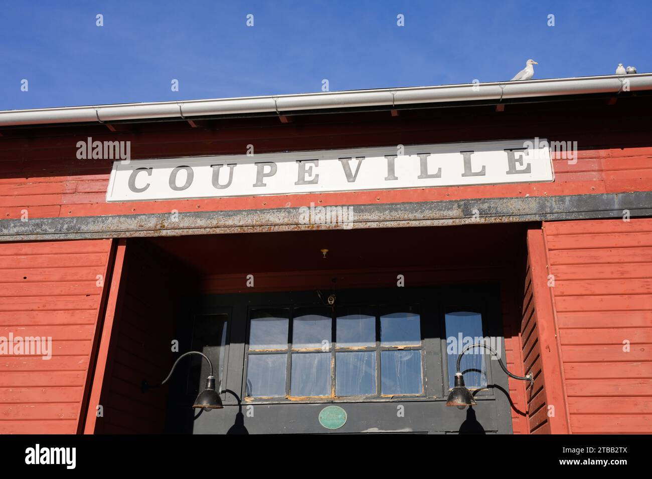 Coupeville, WA, USA - 14 novembre 2023 ; panneau pour la ville de Coupeville sur un bâtiment rouge avec ciel bleu Banque D'Images