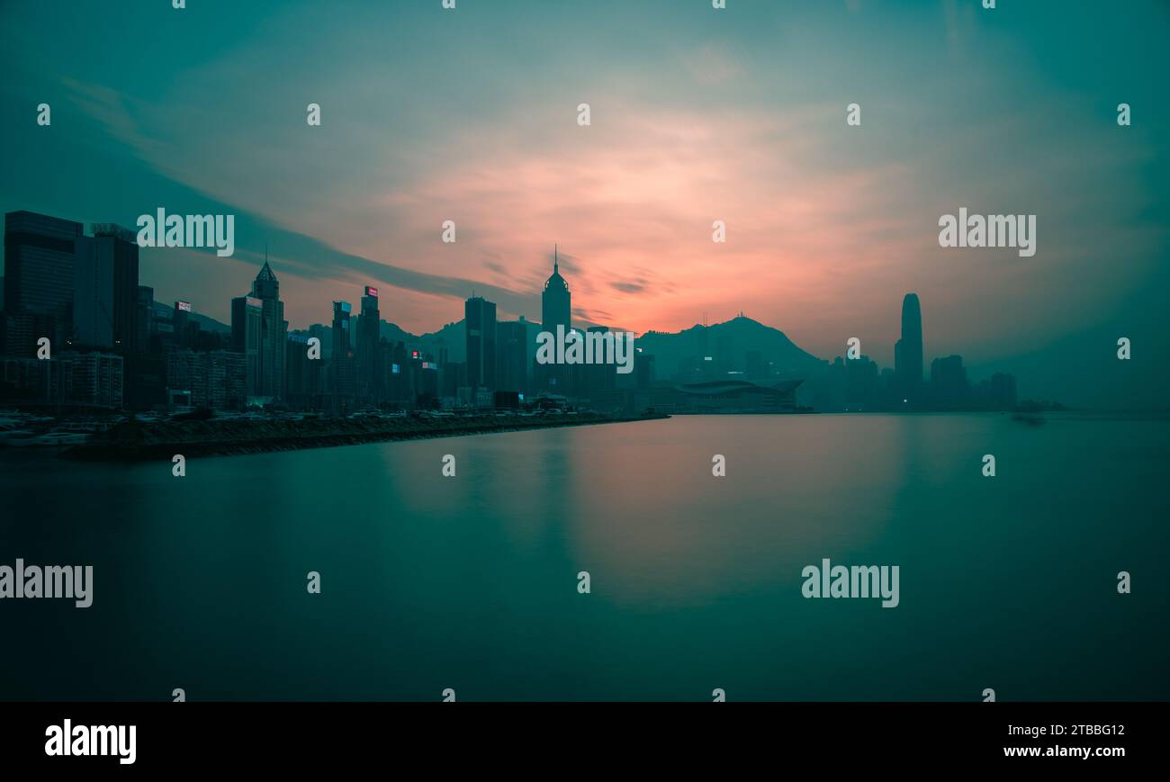 Ciel rose et orange au-dessus de l'île de Hong Kong avec mer lisse de longue exposition. Banque D'Images