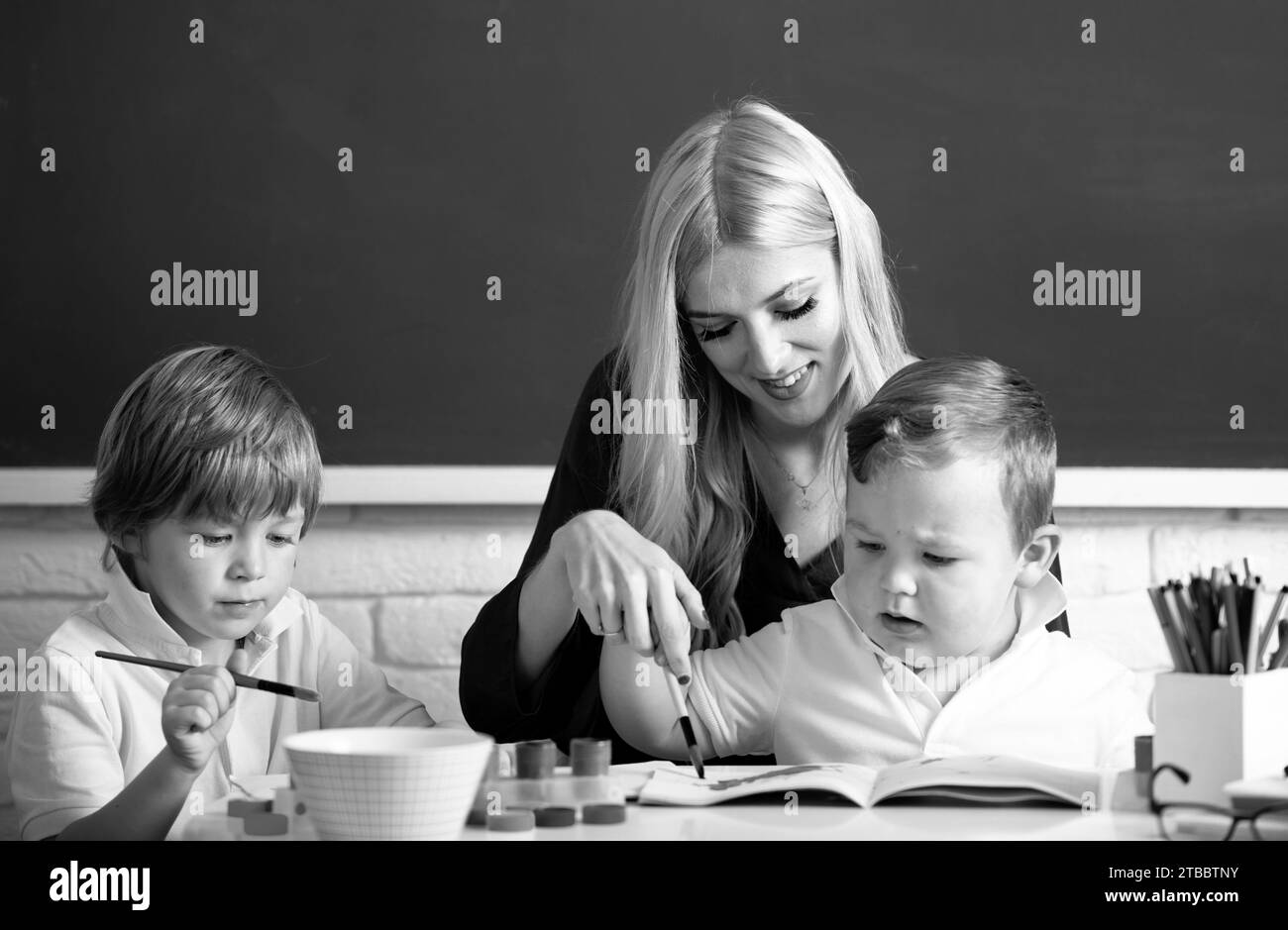 Portrait d'écoliers et d'enseignants parlant à la leçon d'école. Famille heureuse. Mère et deux fils dessinent, peignent. Maman aide les enfants garçons Banque D'Images