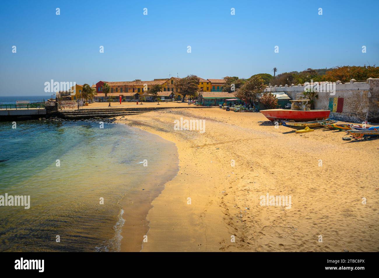Plage de sable sur l'île de Gorée avec des bâtiments colorés et des bateaux Banque D'Images