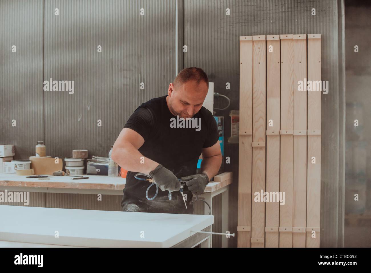 Un travailleur dévoué dans l'industrie du bois emploie l'air comprimé pour nettoyer méticuleusement les produits en bois dans leur phase finale, illustrant Banque D'Images