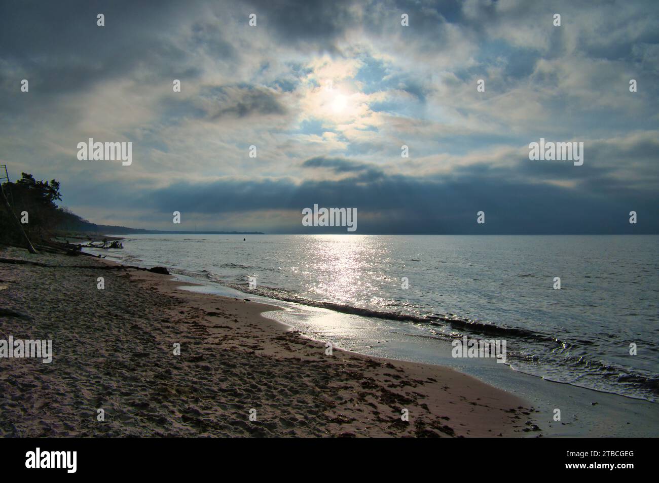 Coucher de soleil sur la plage ouest sur la mer Baltique. Vagues, plage, ciel nuageux et derniers rayons de soleil sur la côte. Photo paysage Banque D'Images