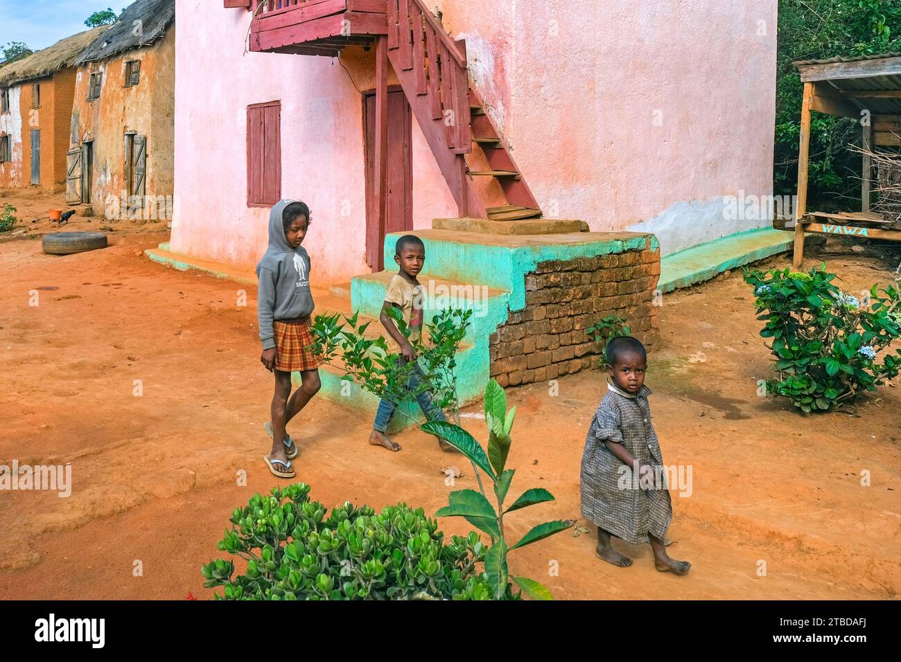 Enfants malgaches dans la rue d'un village rural avec des maisons traditionnelles dans le district d'Ambositra, région d'Amoron'i Mania, Madagascar central, Afrique Banque D'Images