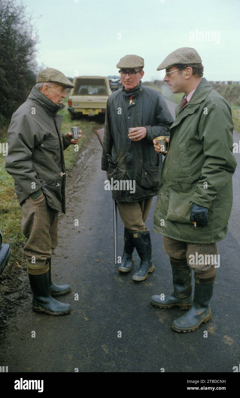 Tir au faisan. Burley on the Hill, un jeu de tir d'oiseau sur le domaine privé de campagne. Tireurs bavardant dans une pause dans le sport de jours, buvant de gobelets d'argent. Burley on the Hill, Oakham, Rutland, Angleterre janvier 1985 1980s Royaume-Uni HOMER SYKES Banque D'Images