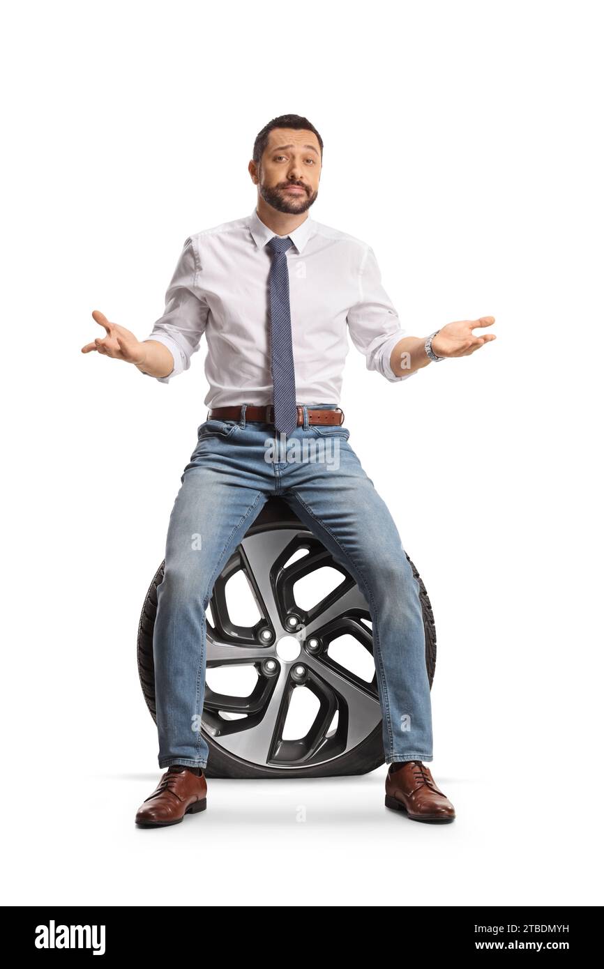 Homme malheureux assis sur un pneu de voiture à plat isolé sur fond blanc Banque D'Images