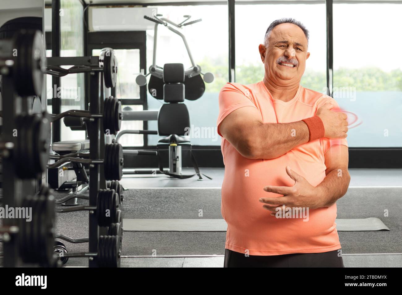 Homme mature en vêtements de sport tenant l'épaule blessée à la salle de gym Banque D'Images