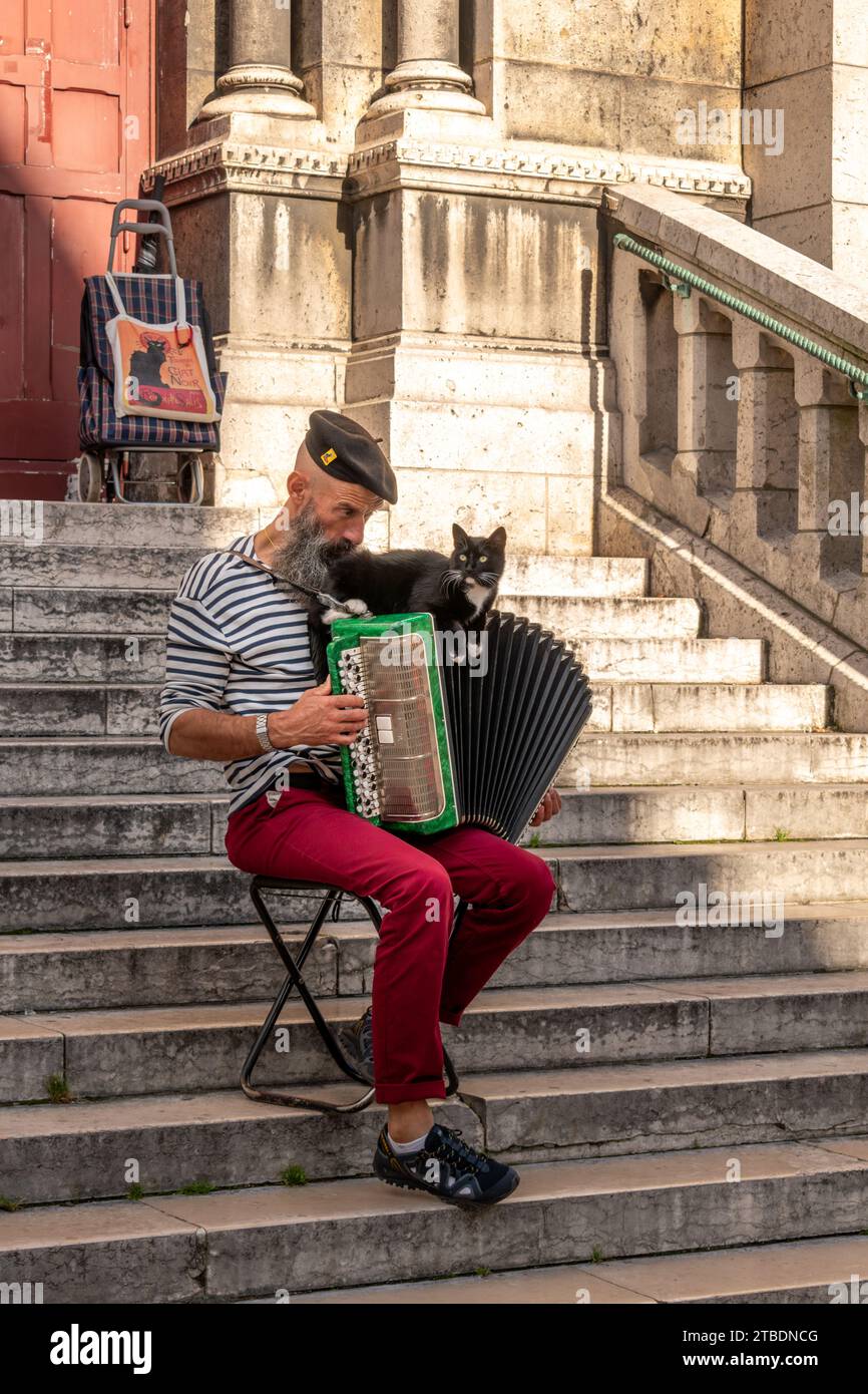 Paris, France - 01 septembre 2023 : musicien de rue joue de l'accordéon avec chat noir sur les escaliers de la basilique du Sacré-cœur à Montmartre Banque D'Images