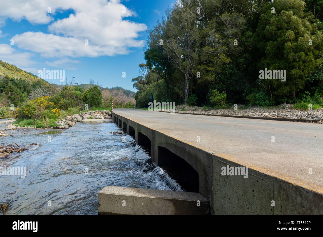 Fond automobile ou plaque arrière comportant une route rurale avec un pont bas courant sur un ruisseau ou une rivière Banque D'Images