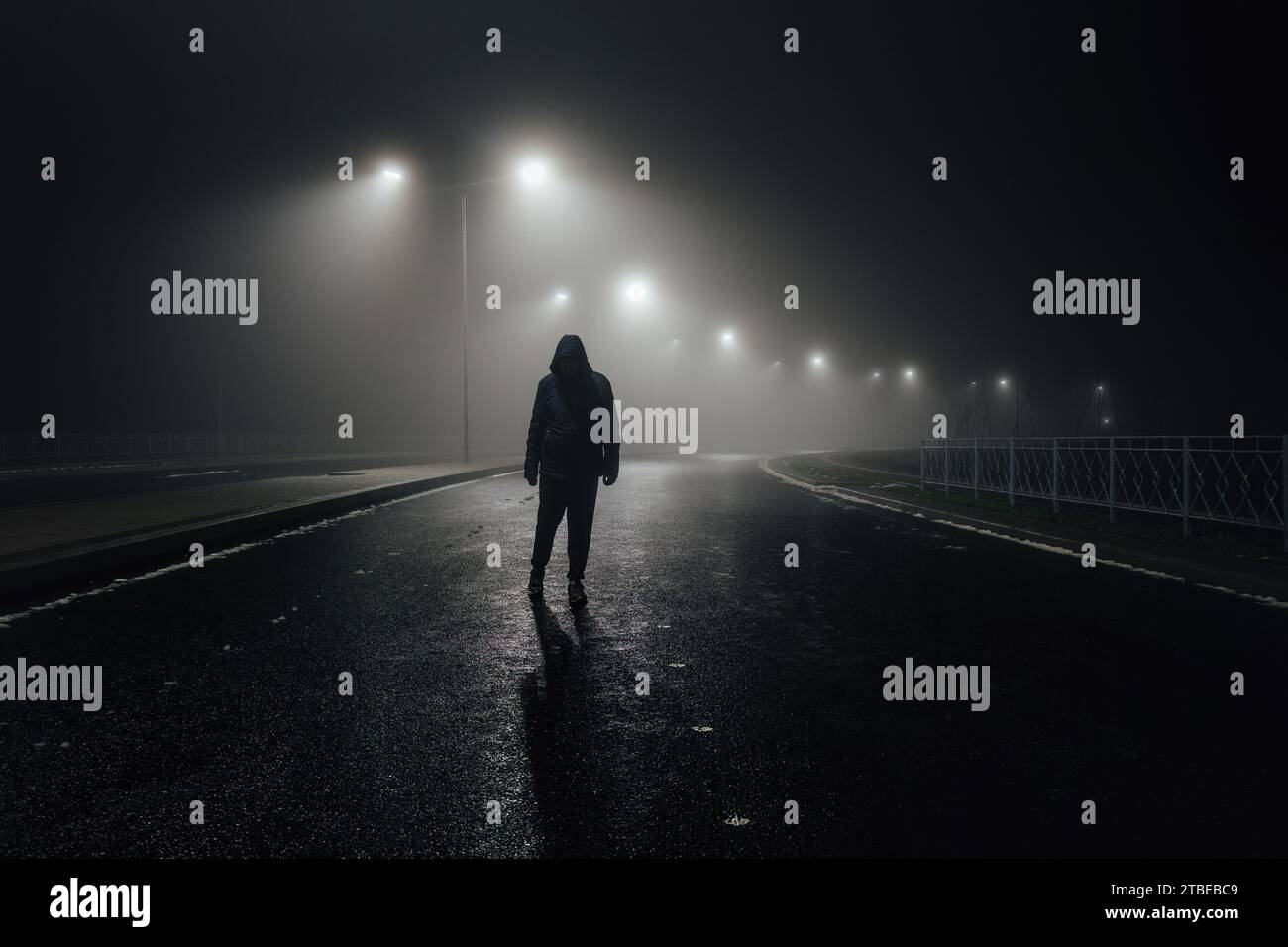 Homme triste seul marchant le long de la ruelle dans la route brumeuse de nuit Banque D'Images