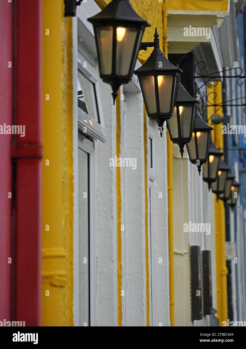 ligne de façades peintes de couleurs vives de bleu, jaune et rouge avec des cadres de fenêtres blancs sous des lanternes à l'ancienne sur la façade de bord de mer Banque D'Images