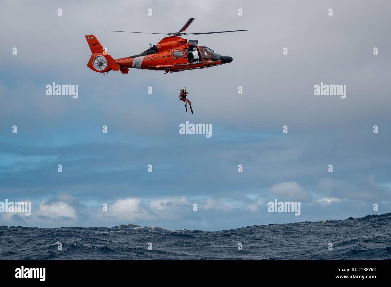 Un H-65 de Air Station Barbers point effectue des helo-OPS avec un petit bateau sous contrat au large de la côte nord d'Oahu, Hawaï. Air Station Barbers point a mené une formation de nageur de sauvetage, avec un navire sous contrat de la Garde côtière le 5 décembre 2023. Banque D'Images