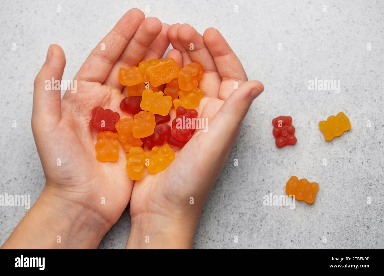 La gomme à mâcher porte des vitamines et des suppléments. Une fille tient un ours gommeux vitamines dans ses mains. Banque D'Images