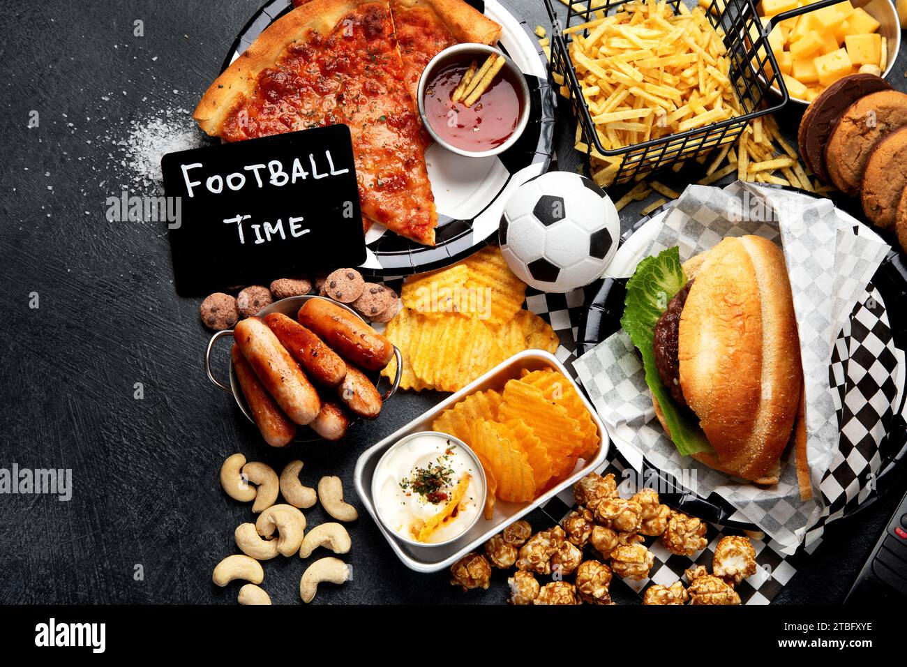 Graisses saturées. L'heure du football. Télécommande TV et collations - chips, pop-corn, biscuits, fromage, sauce, frites, burger, noix. Vue de dessus Banque D'Images