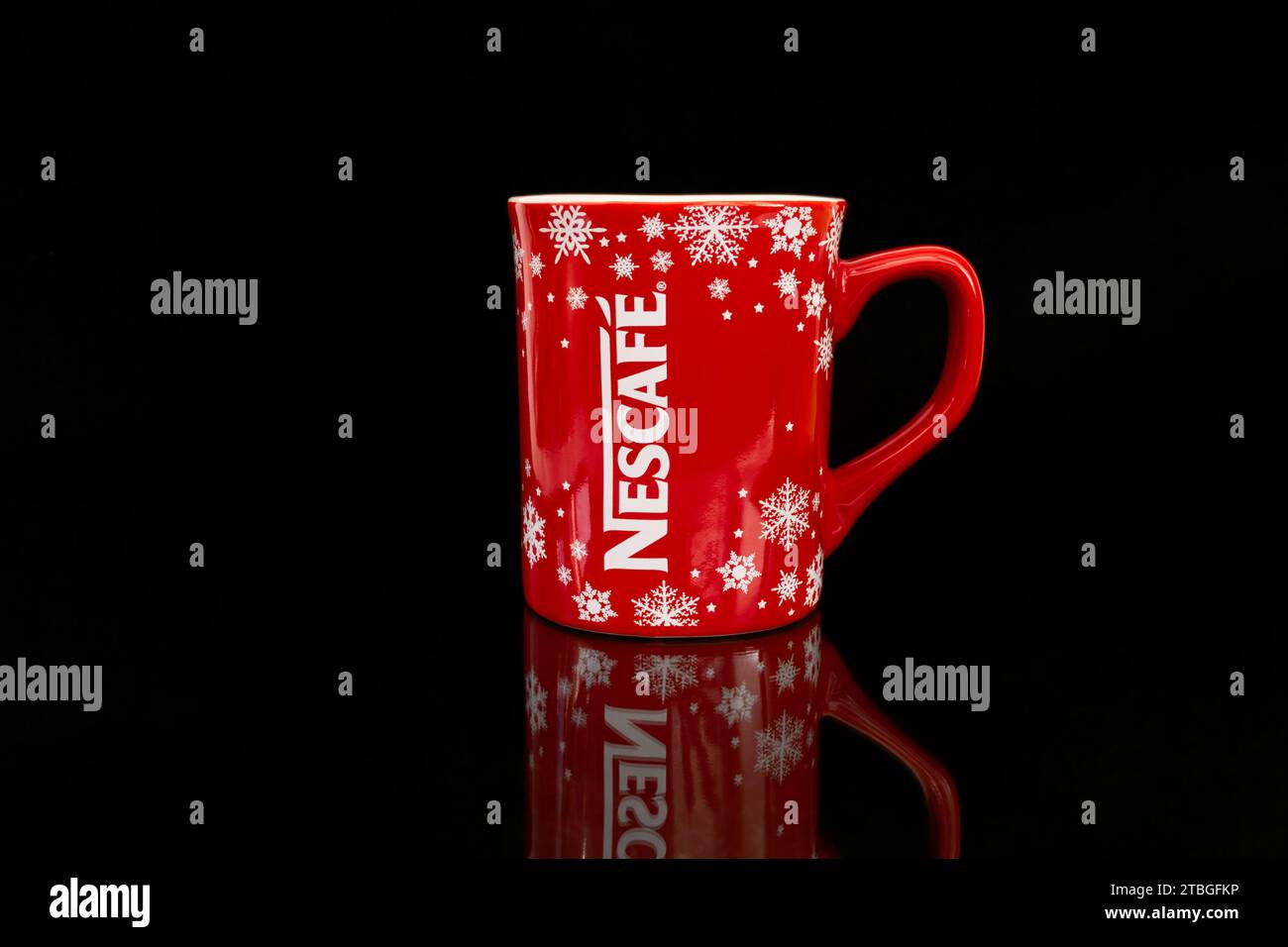 Mug de marque rouge du nouvel an Noël avec logo Nescafe et flocons de neige sur fond noir avec reflets Banque D'Images