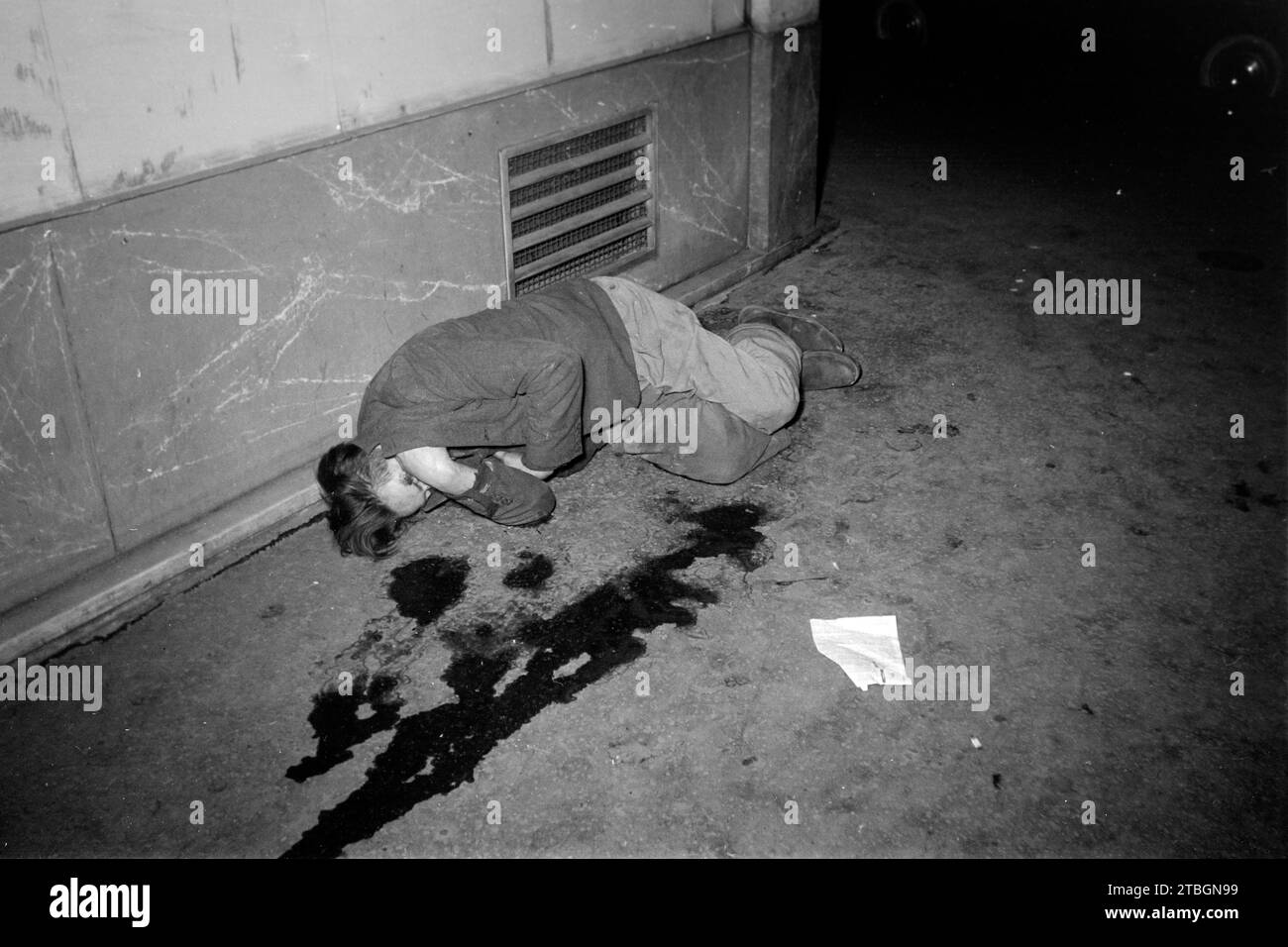 Ein auf der Straße liegender Mann versteckt sich vor der Kamera und dem Blitzlicht, Paris 1962. Un homme allongé dans la rue se cache de l'appareil photo et du flash, Paris 1962. Banque D'Images