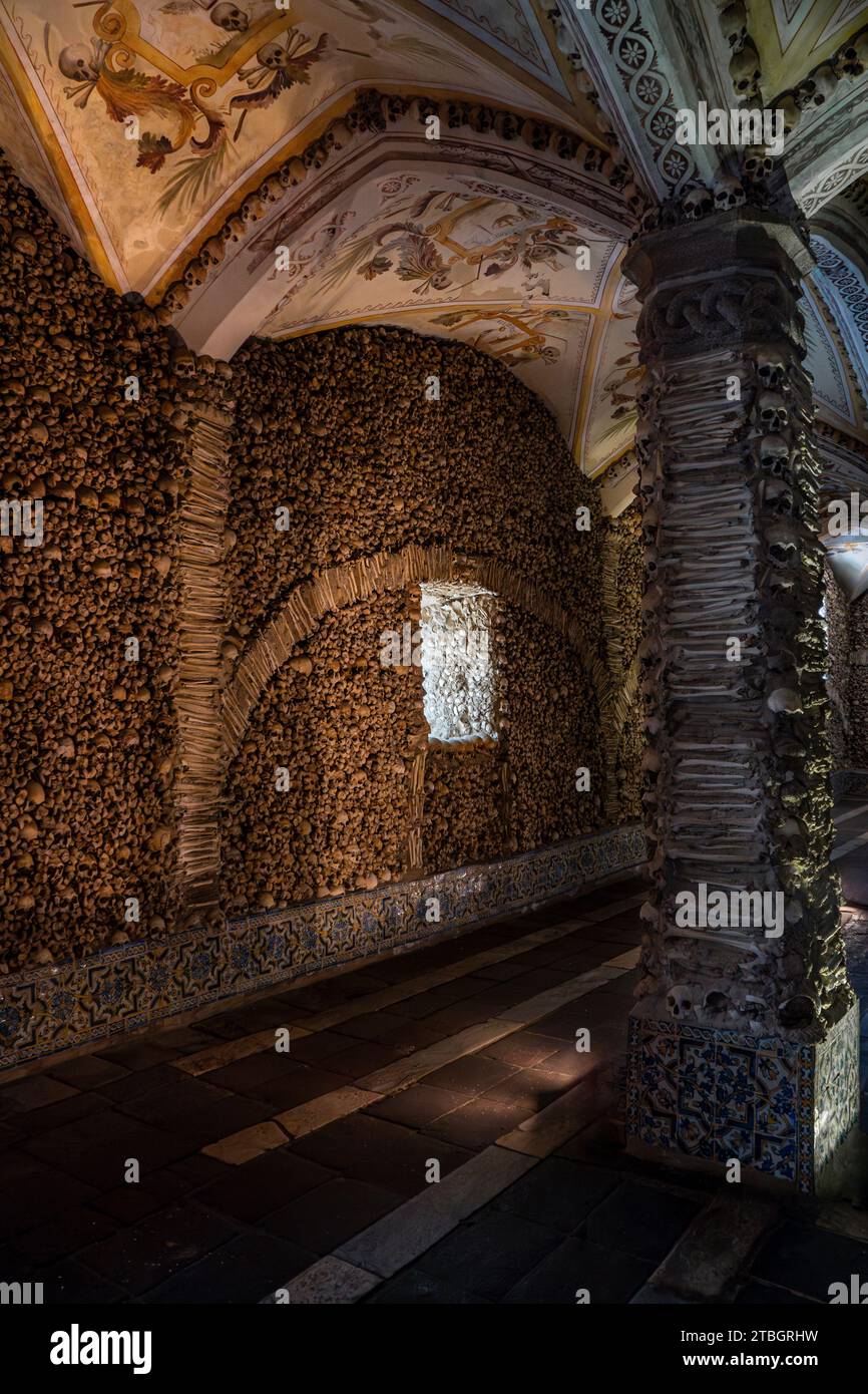 Colonne couverte et décorée d'os humains et de crânes et le plafond voûté avec des peintures allégoriques religieuses de la chapelle des os illuminat Banque D'Images