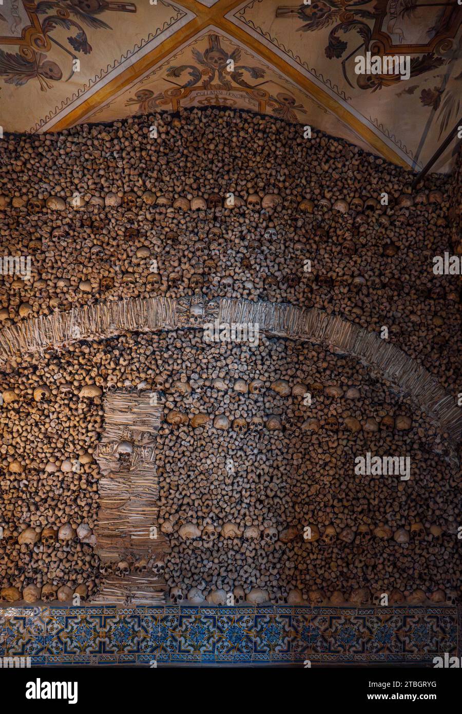 Mur d'os humains et de crânes créant un design en forme d'arc et plafond voûté avec des peintures allégoriques religieuses de la chapelle des os. Evora Banque D'Images