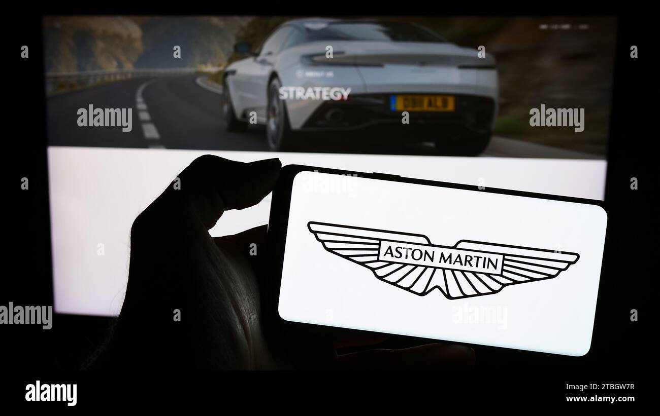 Personne tenant un smartphone avec le logo de la société britannique Aston Martin Lagonda Global Holdings plc devant le site Web. Concentrez-vous sur l'affichage du téléphone. Banque D'Images