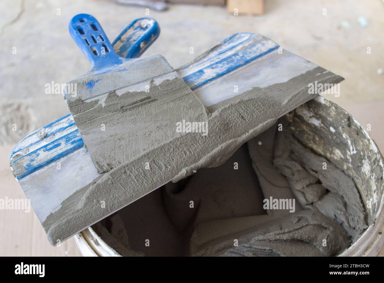 Spatule dans un seau avec de la colle pour carreaux, face aux travaux de montage de carreaux Banque D'Images