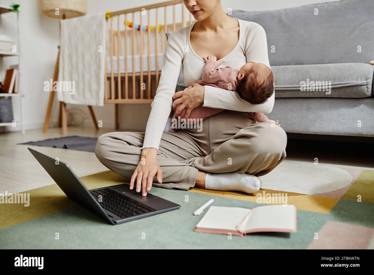 Femme assise sur le sol tenant bébé Banque D'Images