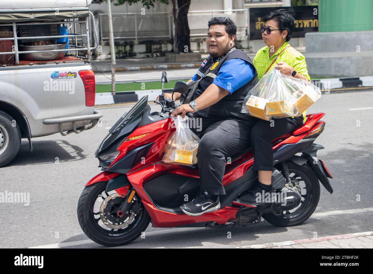 SAMUT PRAKAN, THAÏLANDE, octobre 11 2023, Un couple transporte un achat sur une moto Banque D'Images
