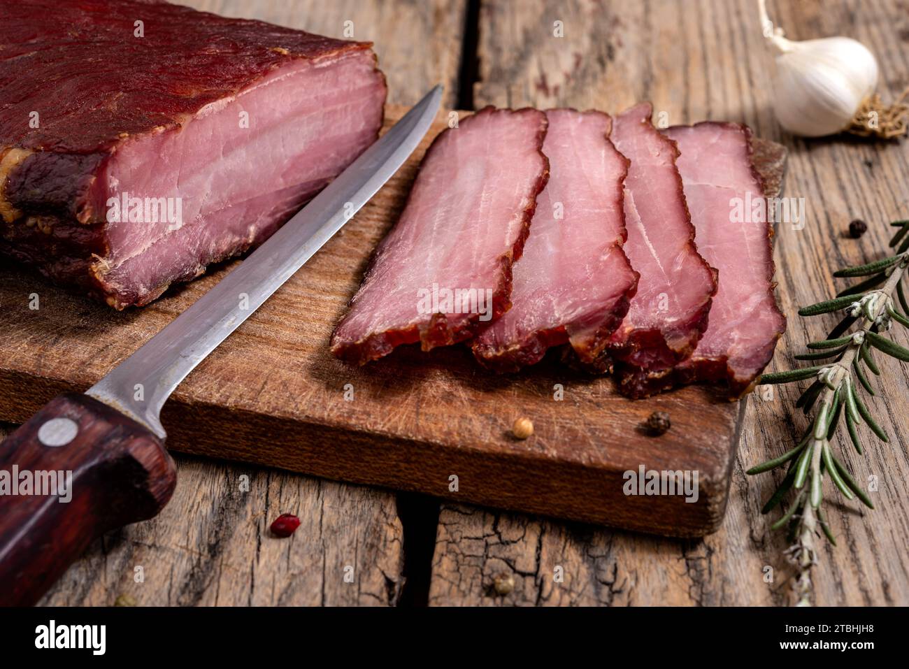 Planche à découper avec de la viande séchée, des épices et un couteau de cuisine sur une table en bois. Mise au point sélective. Banque D'Images
