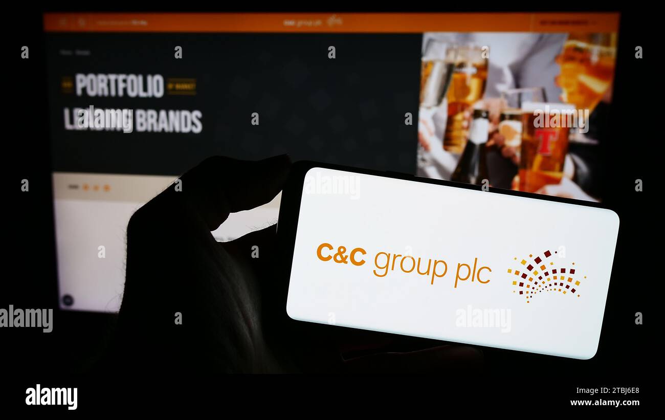 Personne détenant un smartphone avec le logo de la société irlandaise de boissons alcoolisées C et C Group plc (CC) devant le site Web. Concentrez-vous sur l'affichage du téléphone. Banque D'Images