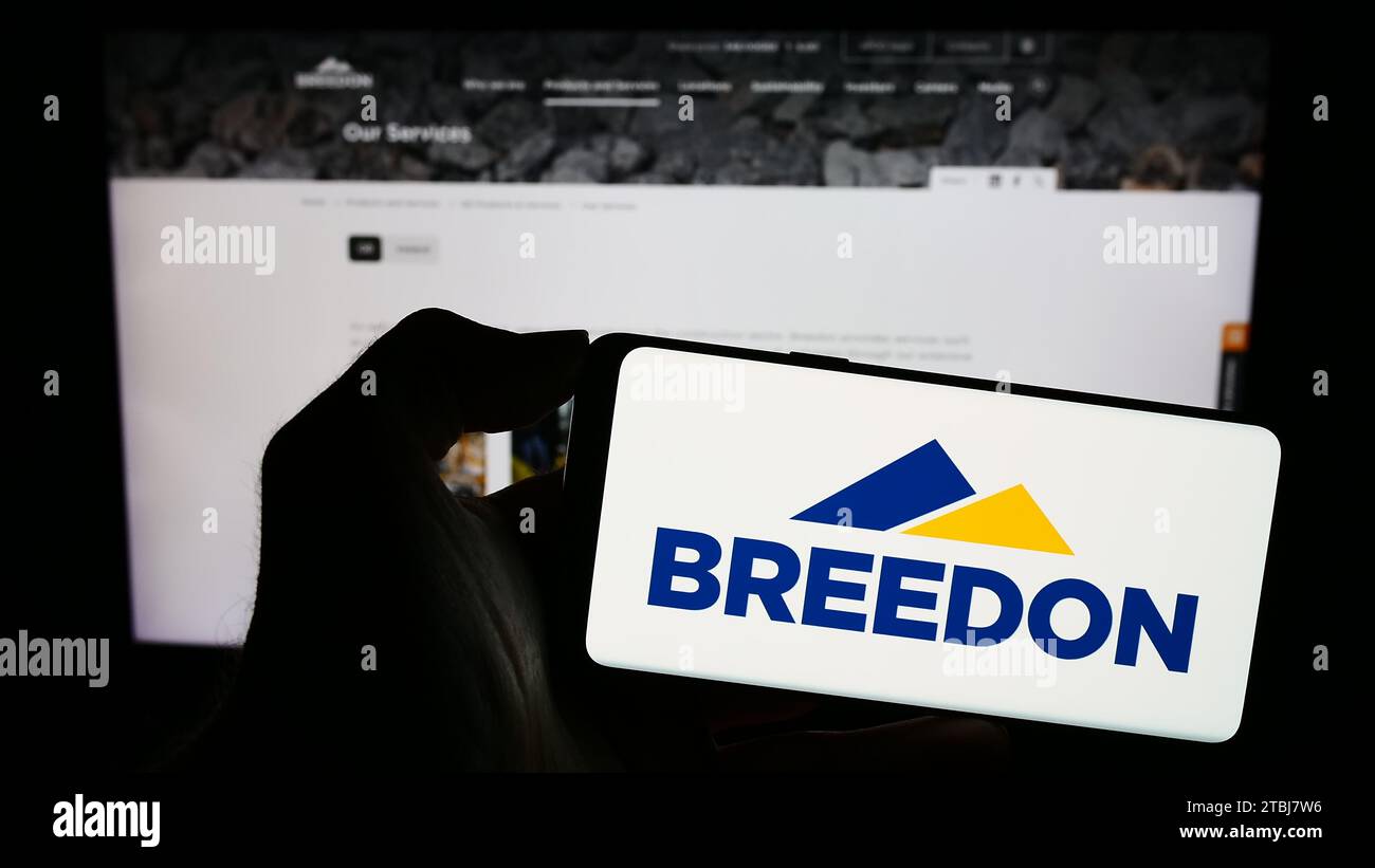 Personne détenant un smartphone avec le logo de la société britannique de matériaux de construction Breedon Group plc devant le site Web. Concentrez-vous sur l'affichage du téléphone. Banque D'Images