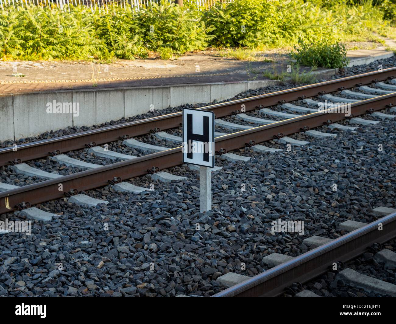 Signe H de la Deutsche Bahn au milieu des rails. Le « Haltetafel » (icône d'arrêt) indique au conducteur du train où arrêter le véhicule sur le quai Banque D'Images