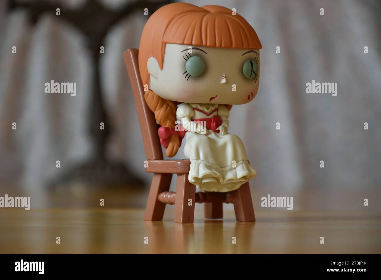Funko Pop figurine d'action de poupée hantée Annabelle des films d'horreur surnaturels évoquant. Intérieur vintage, pièce sombre, vieux chandelier. Banque D'Images