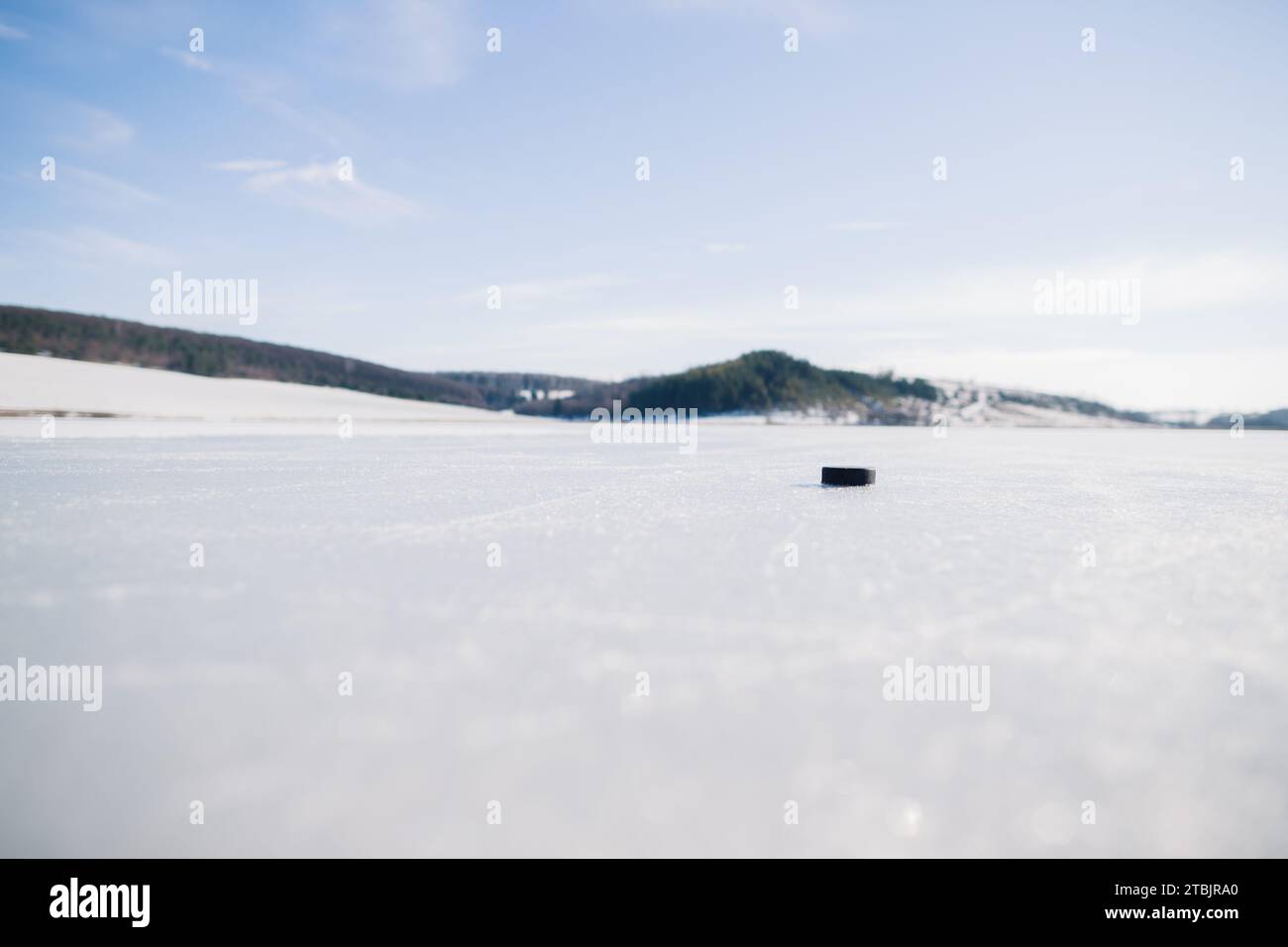 Palet de hockey sur un lac gelé en hiver sur fond de montagnes. Banque D'Images