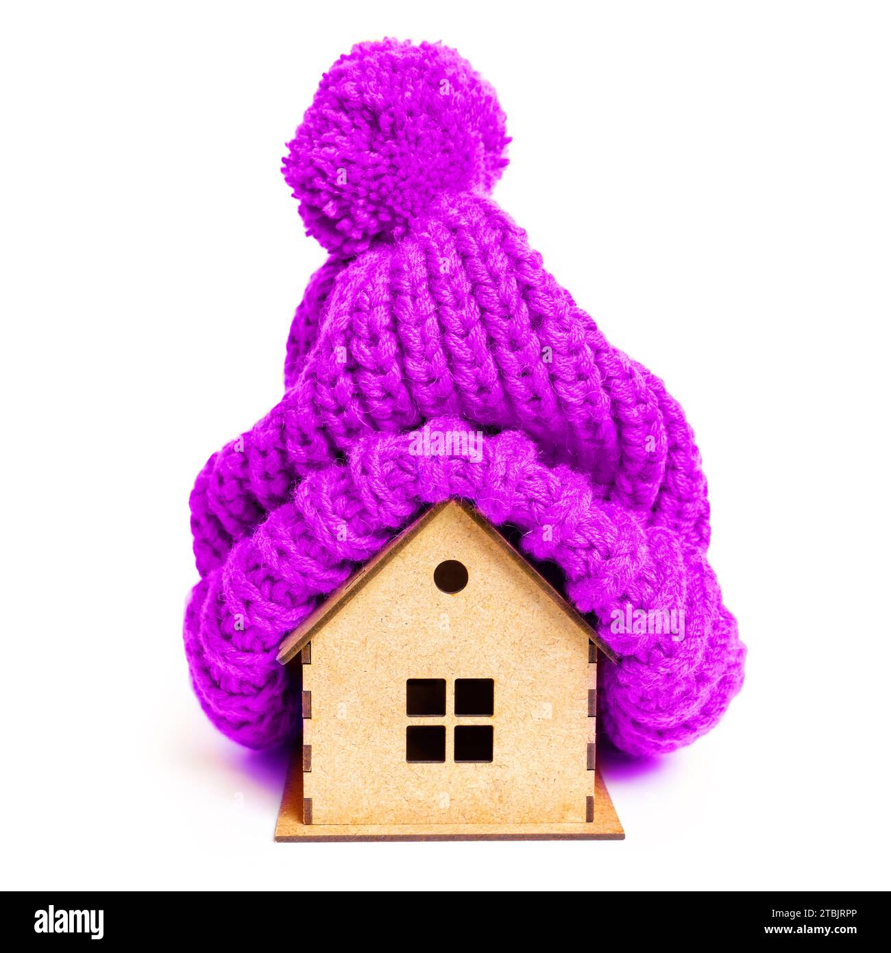Maison en bois jouet portant un chapeau tricoté violet prêt pour l'hiver. Charme saisonnier et concept lié aux vibrations de vacances. Banque D'Images