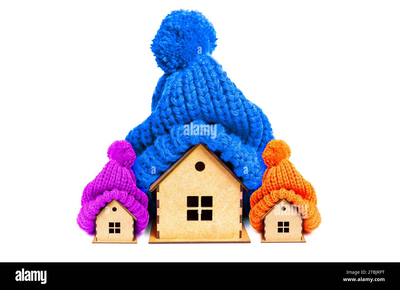 Grande maison et deux petites maisons en bois ornées de chapeaux pompom tricotés vibrants isolés sur fond blanc. Maison familiale, chaleur et confort liés co Banque D'Images