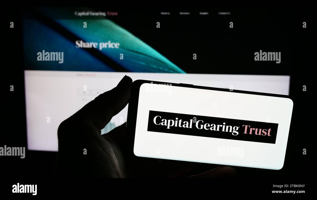 Personne détenant un téléphone portable avec le logo de la société d'investissement britannique Capital Gearing Trust plc (CGT) devant la page Web. Concentrez-vous sur l'affichage du téléphone. Banque D'Images