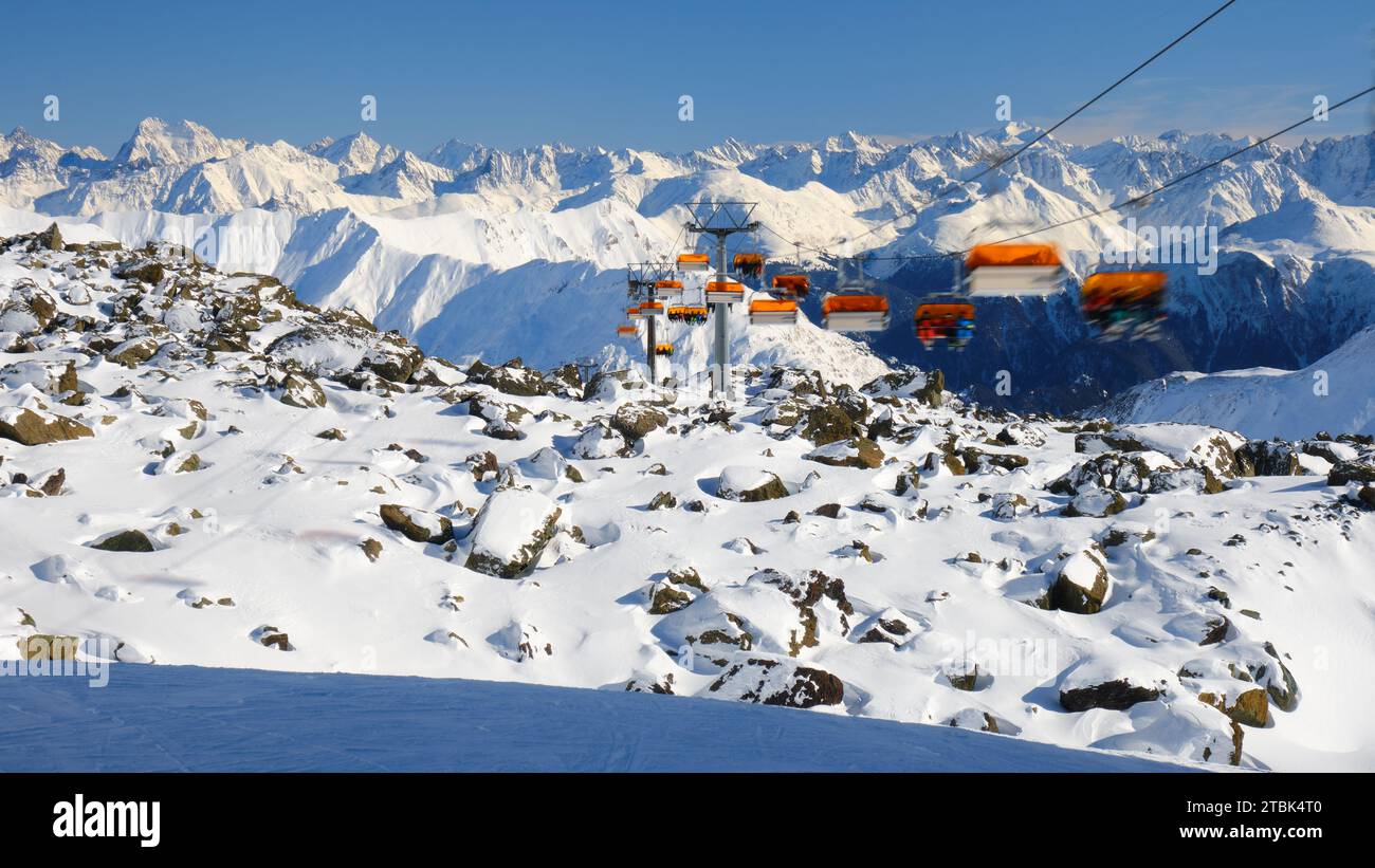 Télésiège orange avec skieurs méconnaissables dans la station de ski Samnaun - Ischgl - Paznaun, située en Autriche et en Suisse. Hiver, ski, télésiège. Banque D'Images