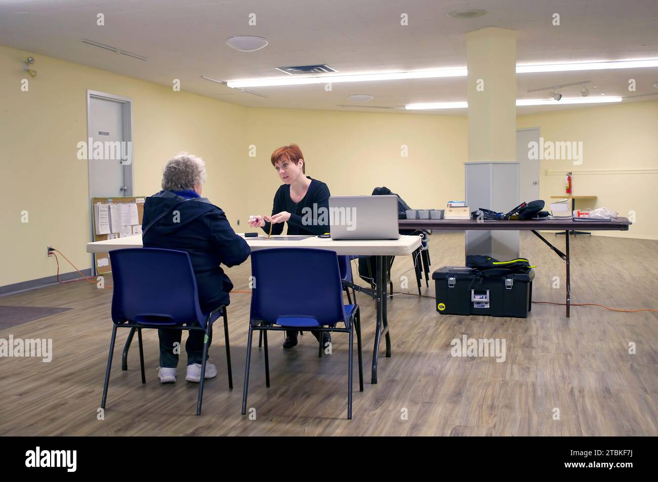 Femme caucasienne plus âgée obtenant une estimation sur un morceau de bijoux d'une jeune évaluatrice féminine avec les cheveux rouges courts. Maple Ridge, B. C., Canada. Banque D'Images