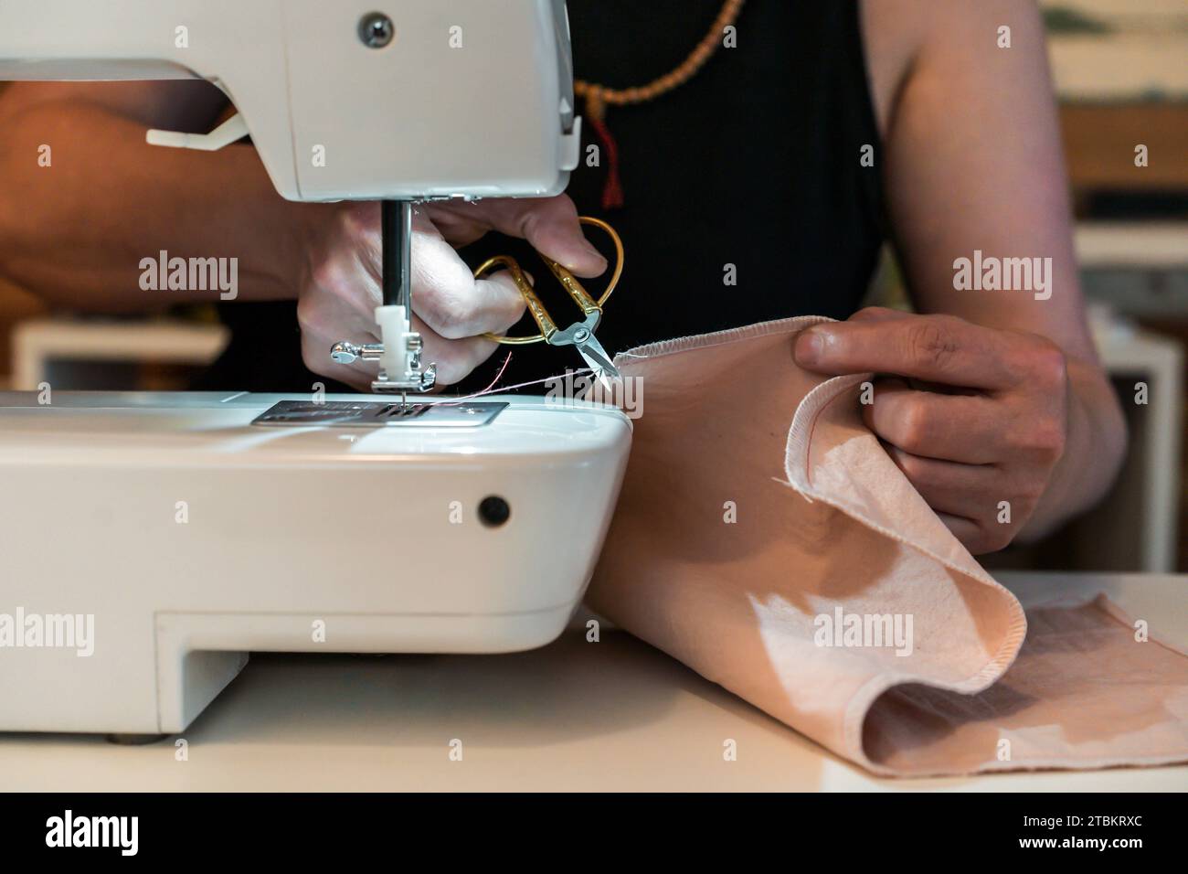 Gros plan pf Femme coupant un fil tout en travaillant avec une machine à coudre Banque D'Images