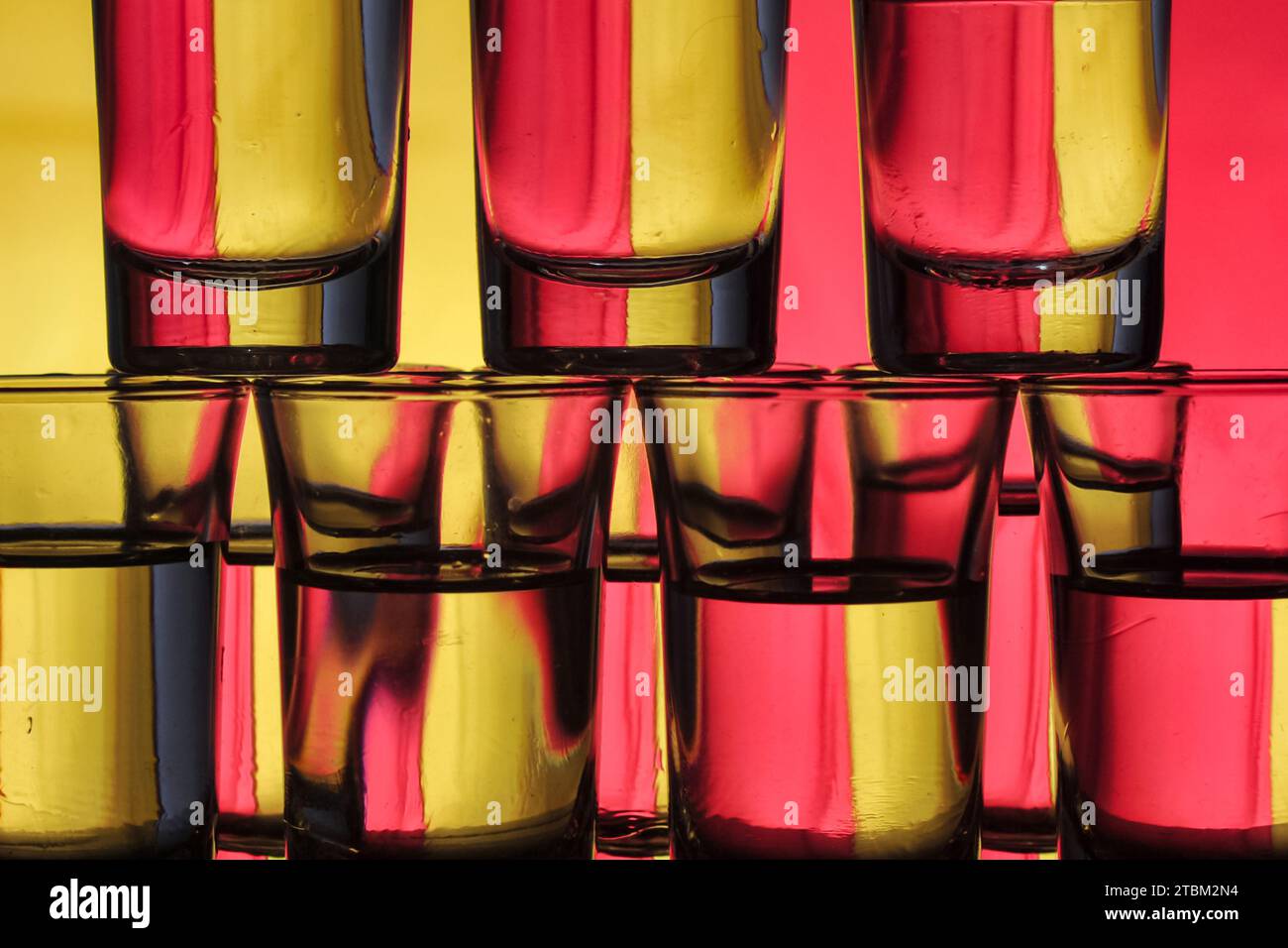 une collection de petits verres remplis d'eau disposés en couches sur un fond bicolore provoque une diffraction de la lumière Banque D'Images