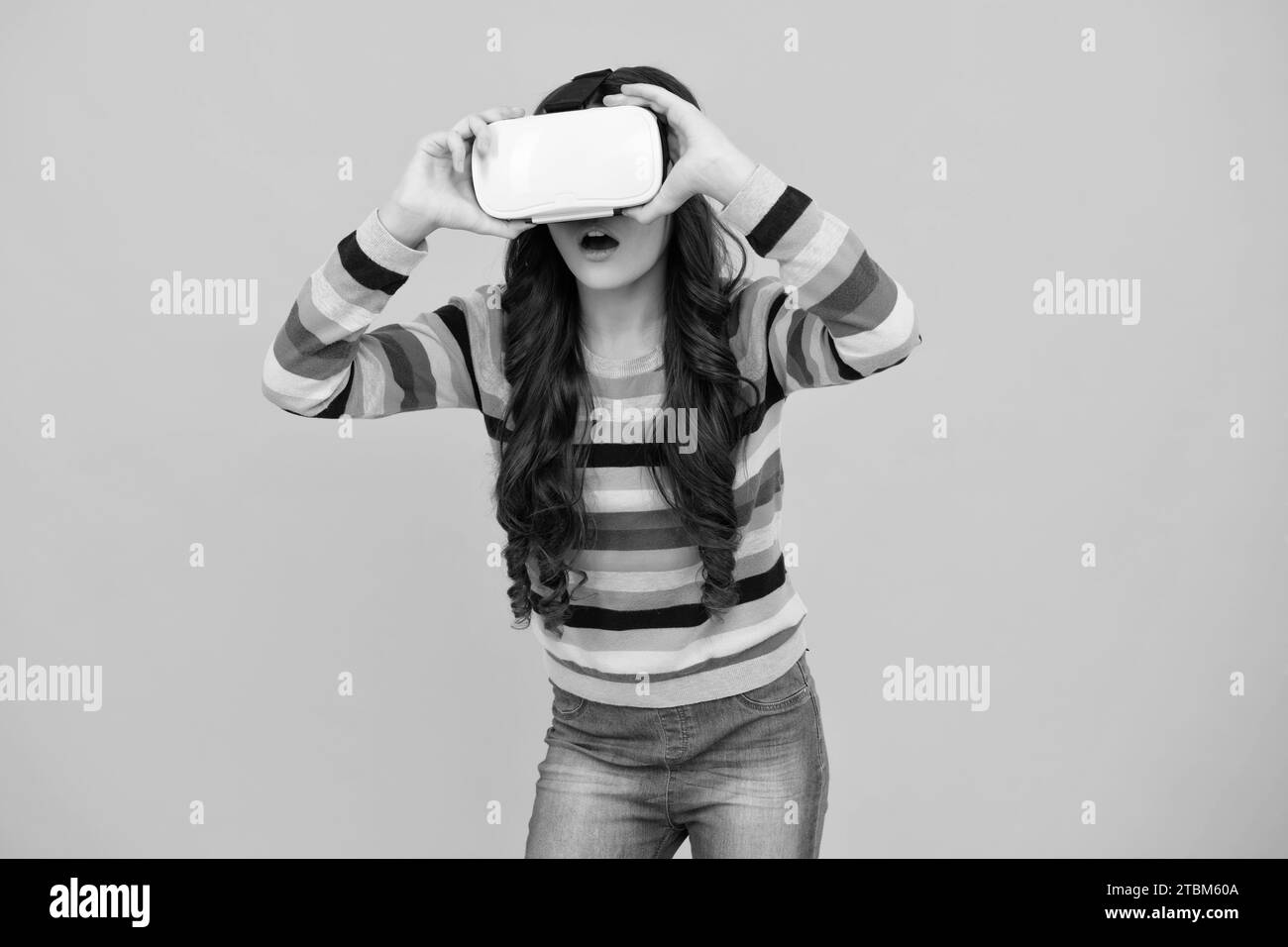 Une jeune fille tient des lunettes vr en utilisant la technologie future pour l'éducation, l'école vr. Drôle adolescent jouant 3D jeux en réalité augmentée. Visage stupéfié Banque D'Images