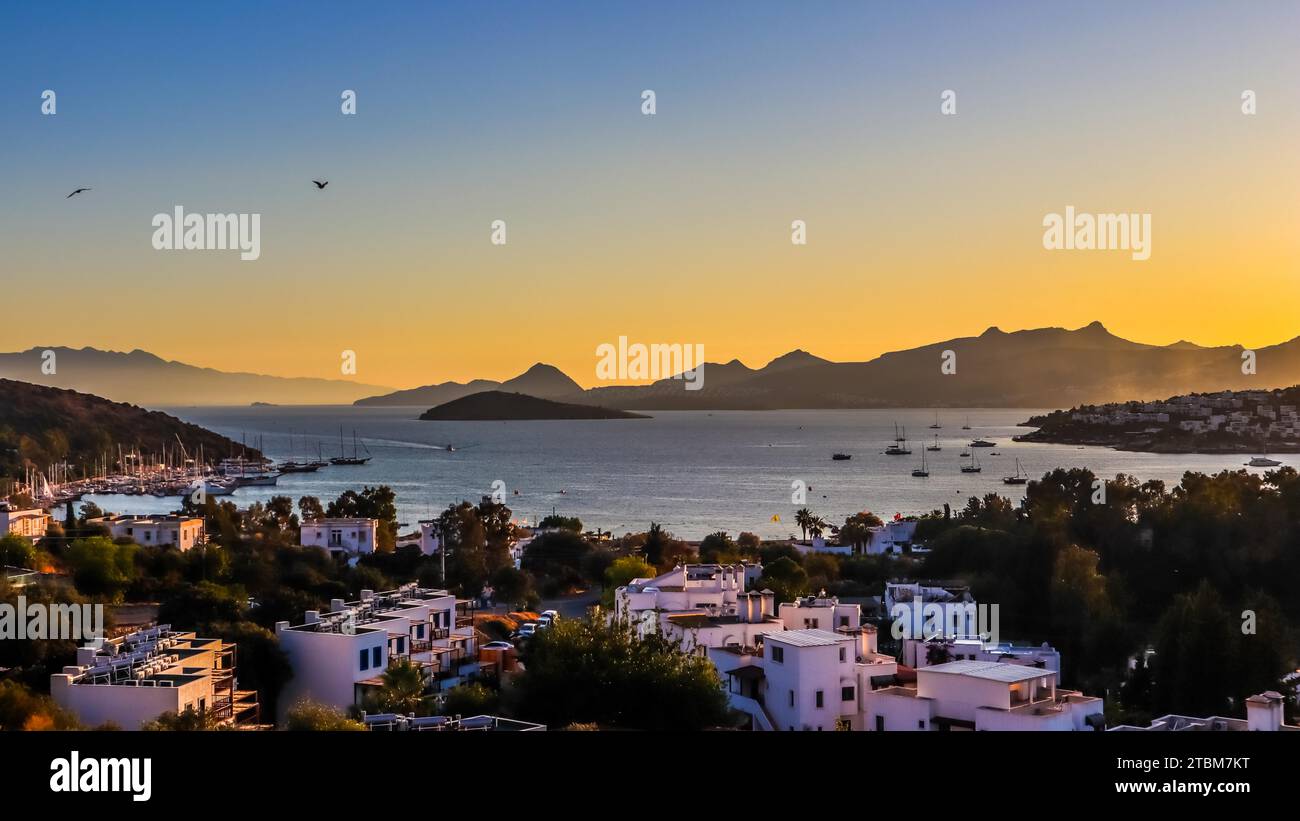 Coucher de soleil coloré lumineux dans la belle baie de la mer Égée avec des îles, des montagnes, des bateaux et des oiseaux dans le ciel, concept de vacances d'été et Voyage Banque D'Images