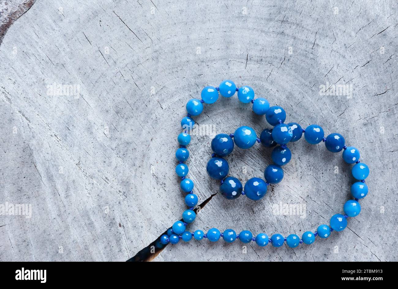 Forme de coeur de collier d'agate facettée bleu foncé sur la surface rugueuse d'une vieille souche. Fond de carte de voeux de Saint-Valentin. Haute qualité Banque D'Images Forme de coeur de collier d'agate facettée bleu foncé sur la surface rugueuse d'une vieille souche. Fond de carte de voeux de Saint-Valentin. Haute qualité Banque D'Images