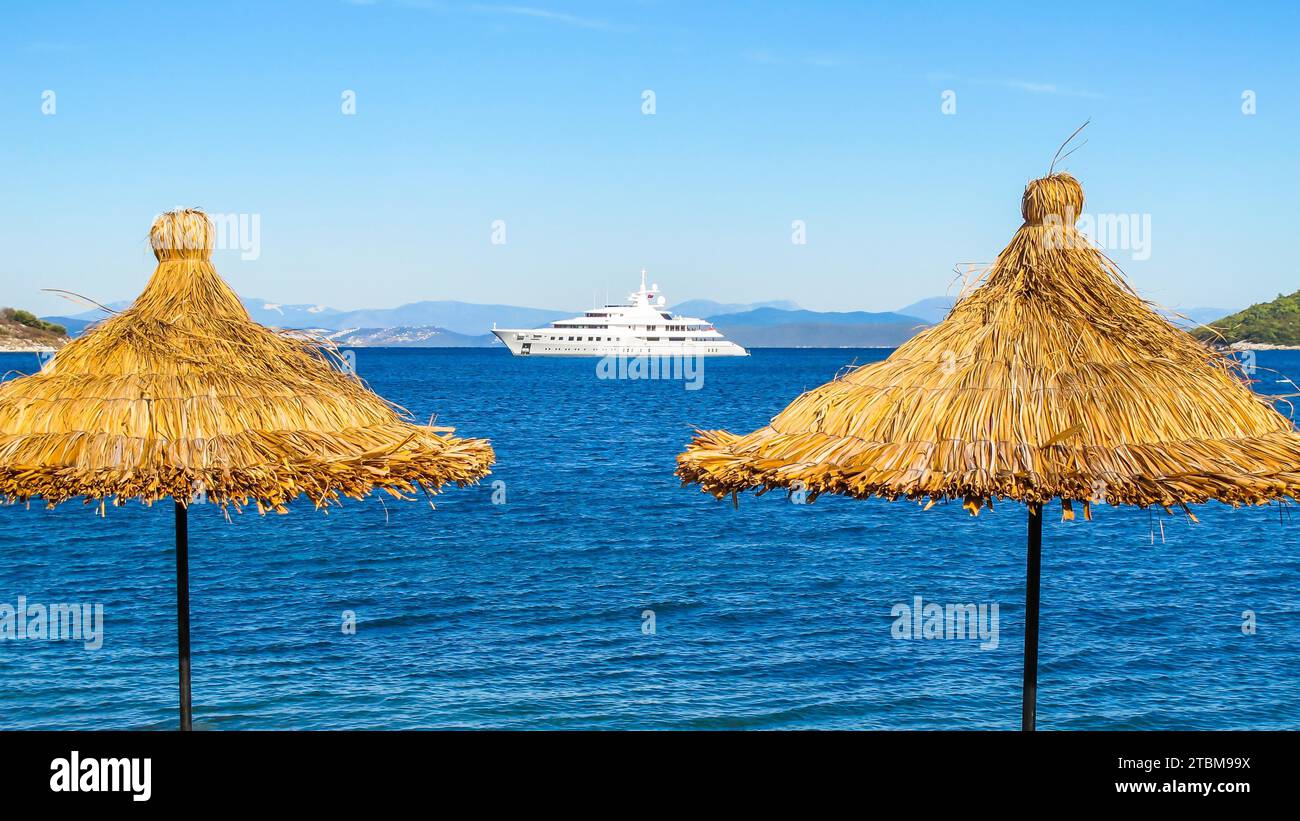 Bleu de la mer avec un bateau blanc paille et des parasols sur la plage Banque D'Images Bleu de la mer avec un bateau blanc paille et des parasols sur la plage Banque D'Images