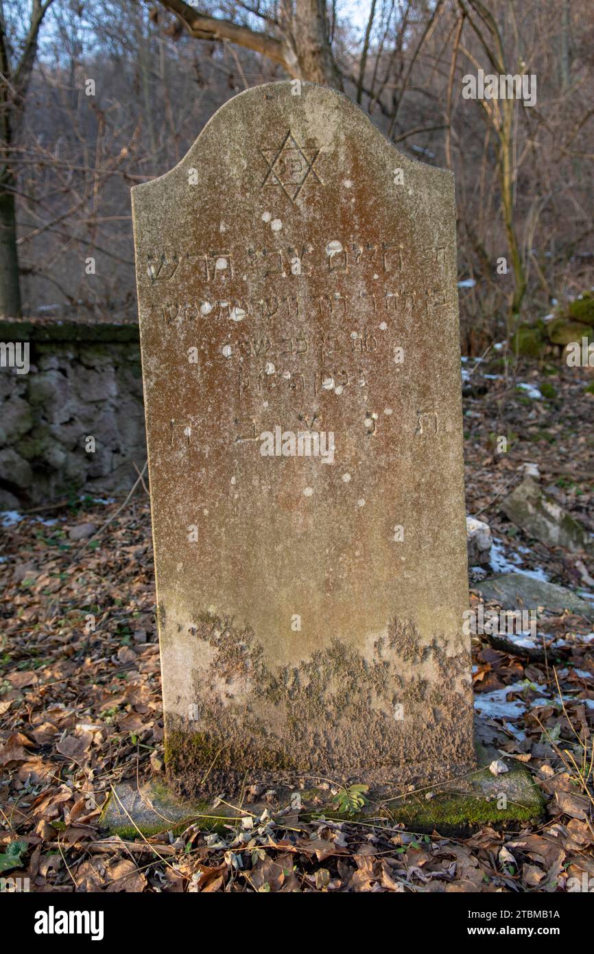 Ancien ancien cimetière juif abandonné dans la forêt en hiver. Pierres tombales ou pierres tombales âgées dans le cimetière Banque D'Images