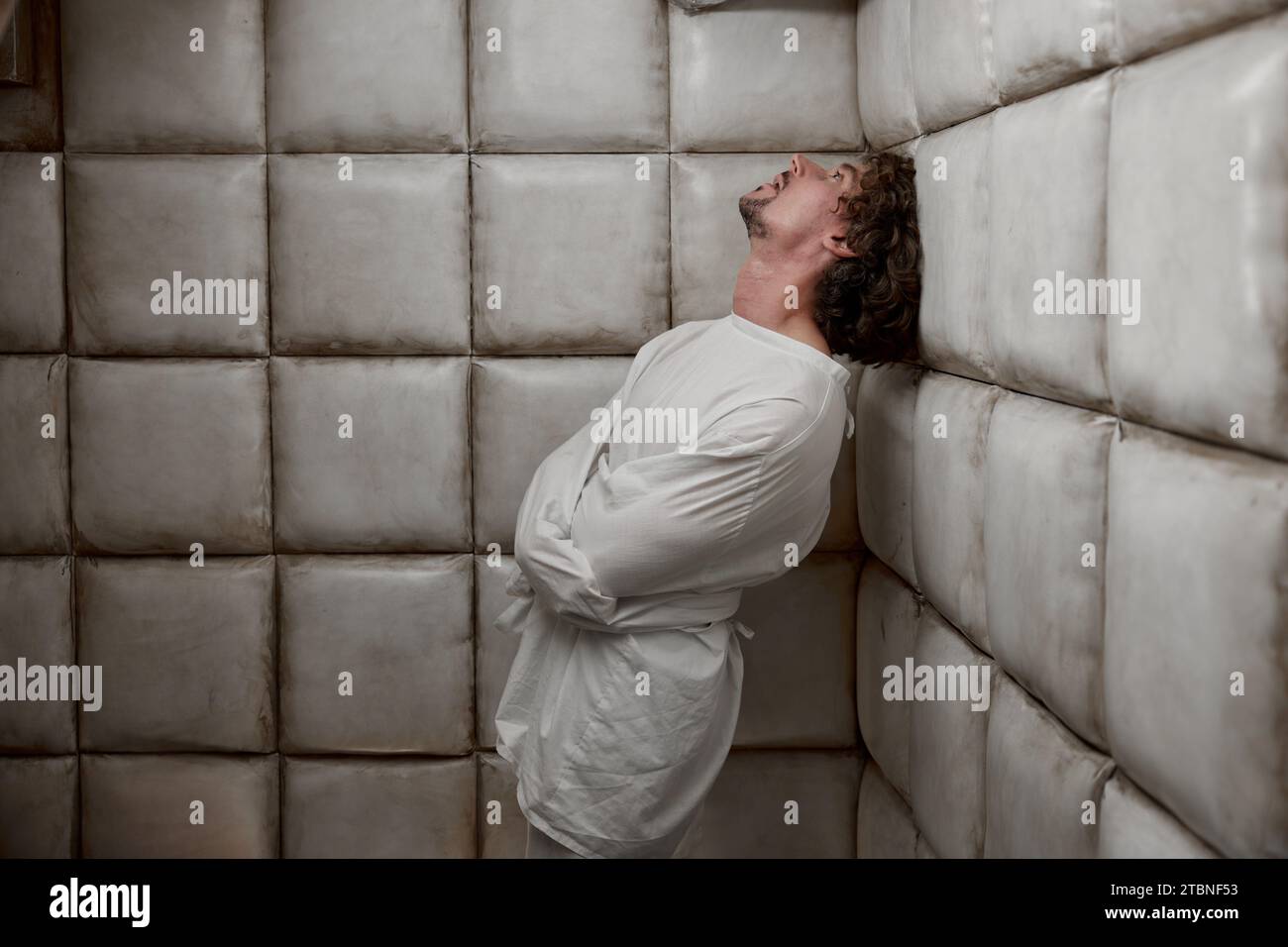 Homme calme avec un trouble mental de schizophrénie dans une chambre blanche rembourrée Banque D'Images