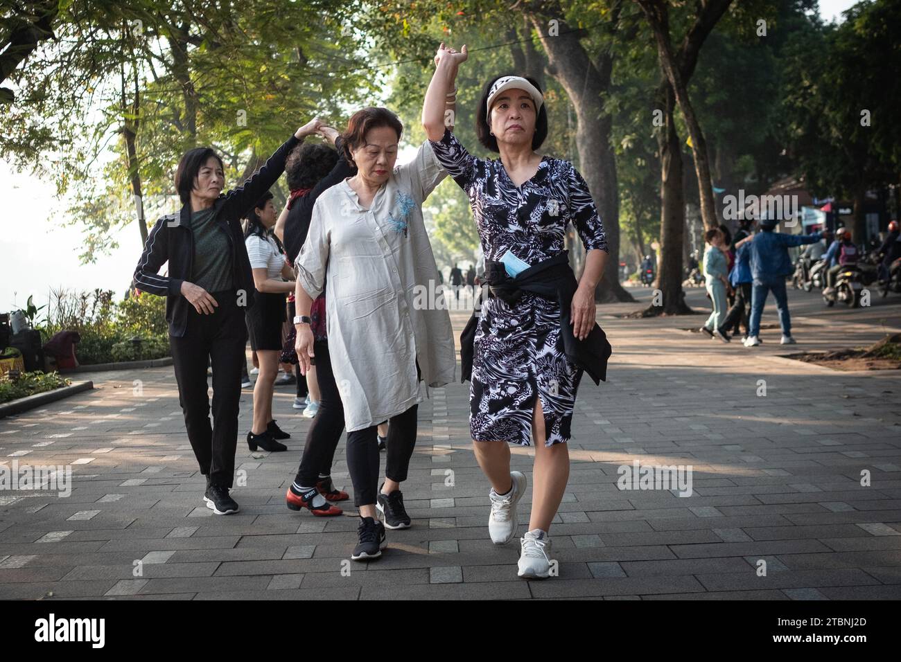 Les femmes tiennent un cours de danse sur le bord du lac Hoan Kiem à Hanoi tôt vendredi dans le cadre de leur routine d'exercice. De nombreux résidents de la capitale vietnamienne dansent et font de l'exercice autour des rives des lacs de la ville au lever du soleil. Date de la photo : Vendredi 8 décembre 2023. Banque D'Images
