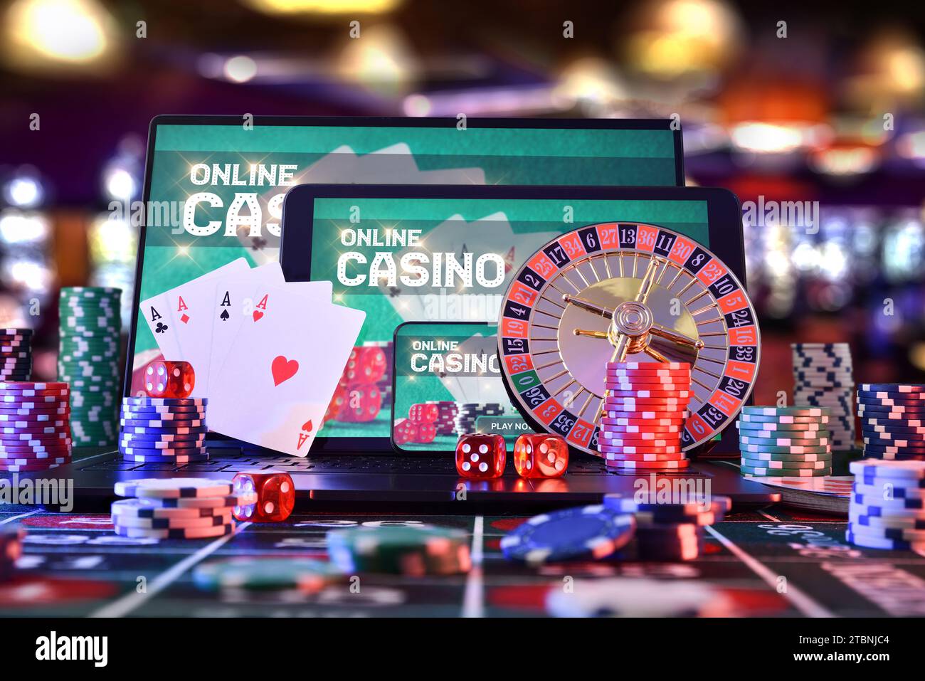 Dispositifs électroniques pour jeu de casino en ligne avec application sur l'écran sur la table de jeu avec jetons, cartes, dés et roulette dans une salle de jeux. Vue avant. Banque D'Images